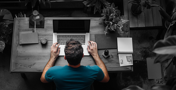 Foto von Person am Schreibtisch, die auf ein Notebook schaut